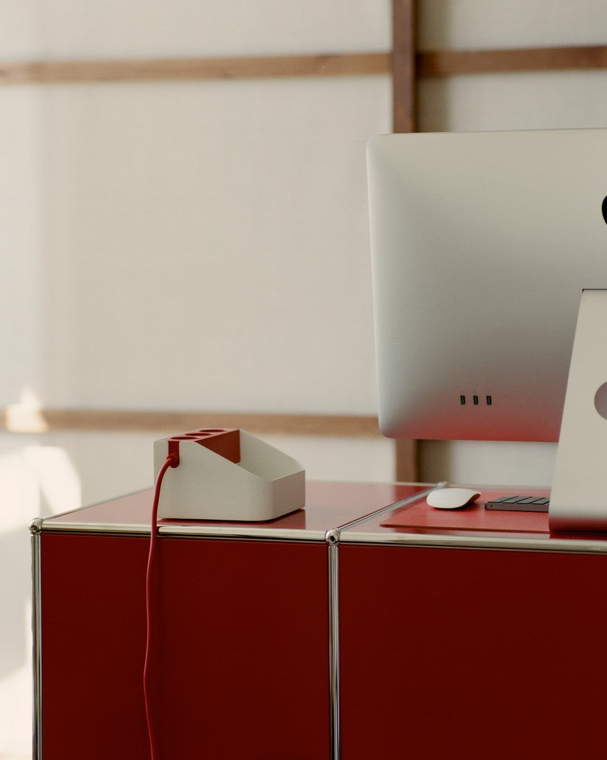 Power Bar Tray in Pearl su credenza rossa in ambiente ufficio, con cavo rosso e iMac accanto sulla scrivania
